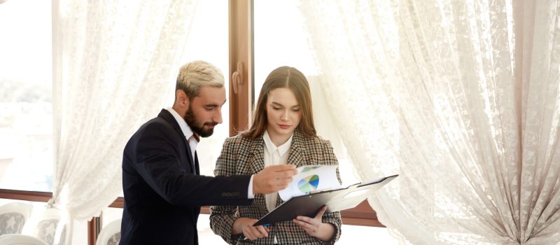 Handsome man and a brunette woman are looking at the diagramme, being in the light room