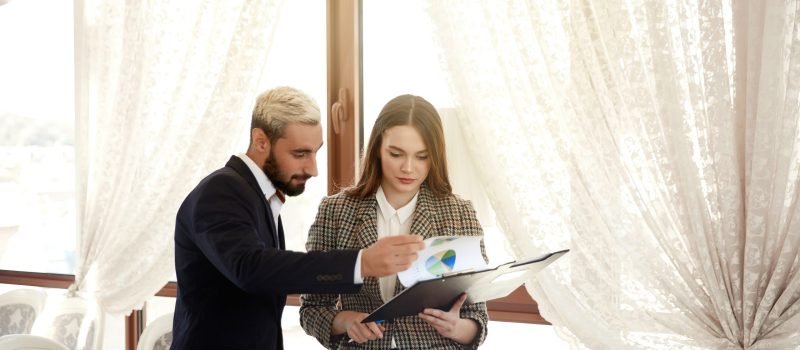 Handsome man and a brunette woman are looking at the diagramme, being in the light room